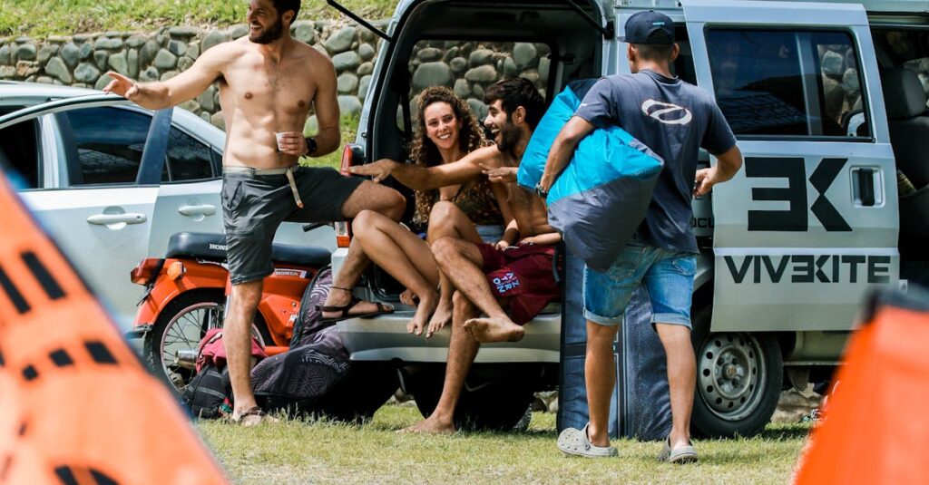 Friends enjoying a sunny day outside, seated by a van with kite gear, capturing a relaxed summer vibe.