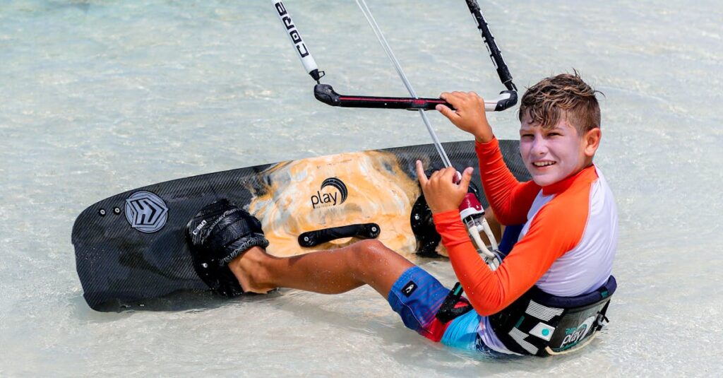 Teenager enjoying kitesurfing on a tropical beach, showcasing skills with a relaxed pose.